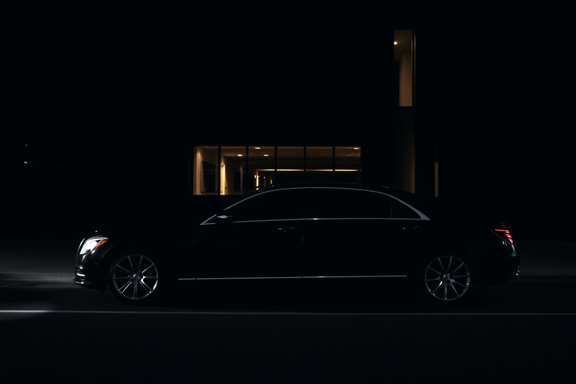 Black executive sedan at night outside a modern building